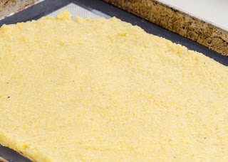 Cooked polenta spread out on a sheet pan