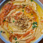 Bowl of hummus with pine nuts, olive oil and parsley